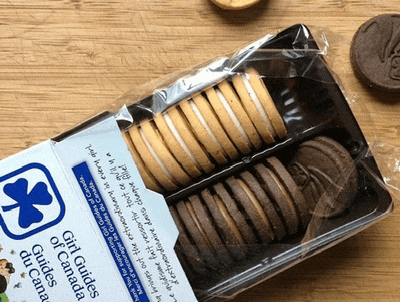 a box of girl guides cookies sits on a wooden surface