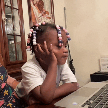 a little girl sitting in front of a laptop computer