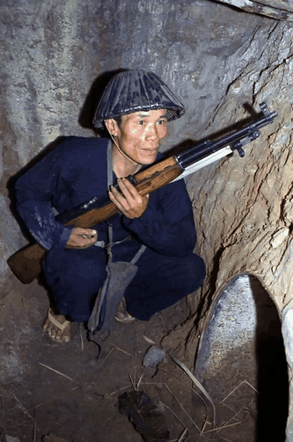 a man wearing a helmet and holding a gun in a cave