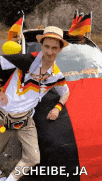 a man in a hat is standing in front of a car with a german flag on the back .