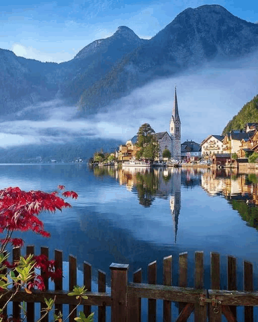 a wooden fence surrounds a lake with a church in the background