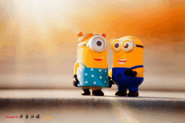 a couple of minions standing next to each other with chinese writing on the bottom right corner