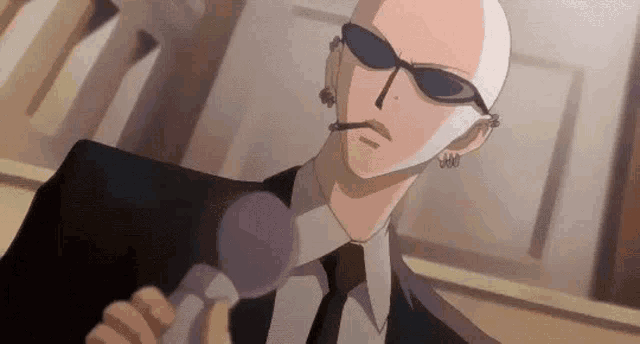 a bald man wearing sunglasses and a suit is holding a microphone and smoking a cigarette .