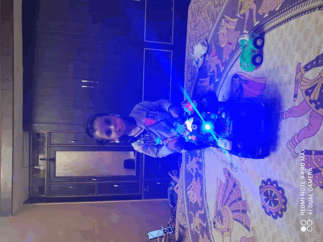 a child is playing with a toy car on a bed with a redmi note 8 pro max