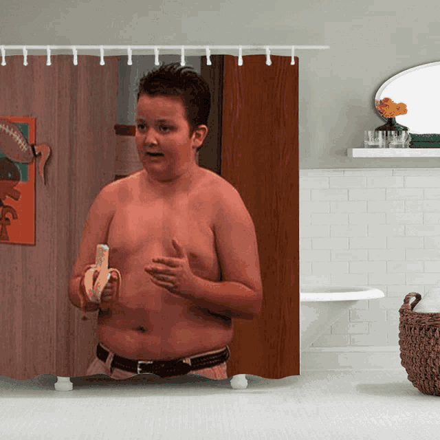 a shower curtain shows a shirtless boy holding a banana in a bathroom