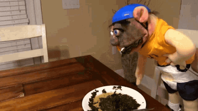 a puppet wearing a yellow shirt and a blue helmet is standing next to a bowl of food