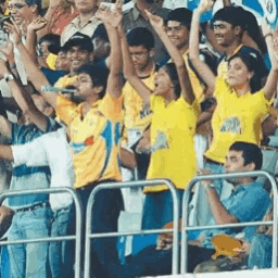 a crowd of people wearing yellow shirts with the word king on them are raising their arms in the air