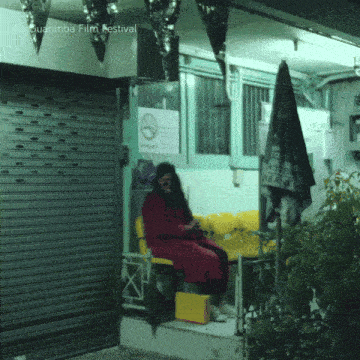 a woman in a red coat sits in front of a sign that says ' no smoking ' on it