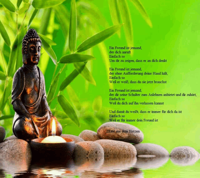 a statue of a buddha sits on some rocks with a candle in front of a green background