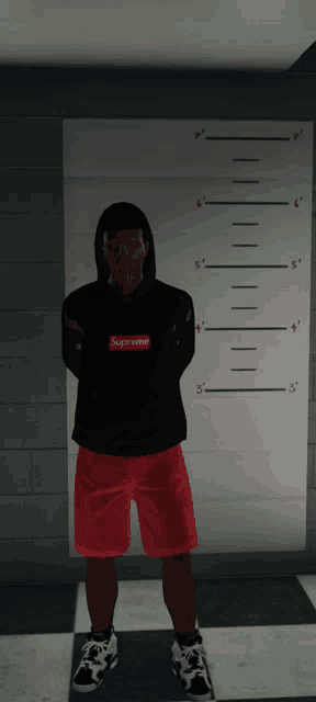 a man wearing a black supreme hoodie and red shorts stands in front of a ruler