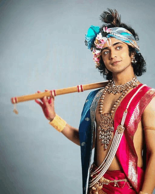 a man dressed as a krishna holds a flute