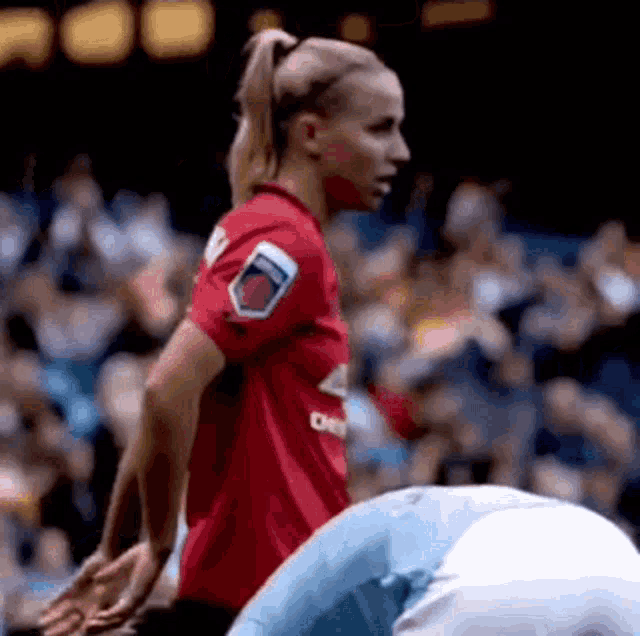 a woman in a red soccer jersey is standing next to a man in a blue shirt on a soccer field .