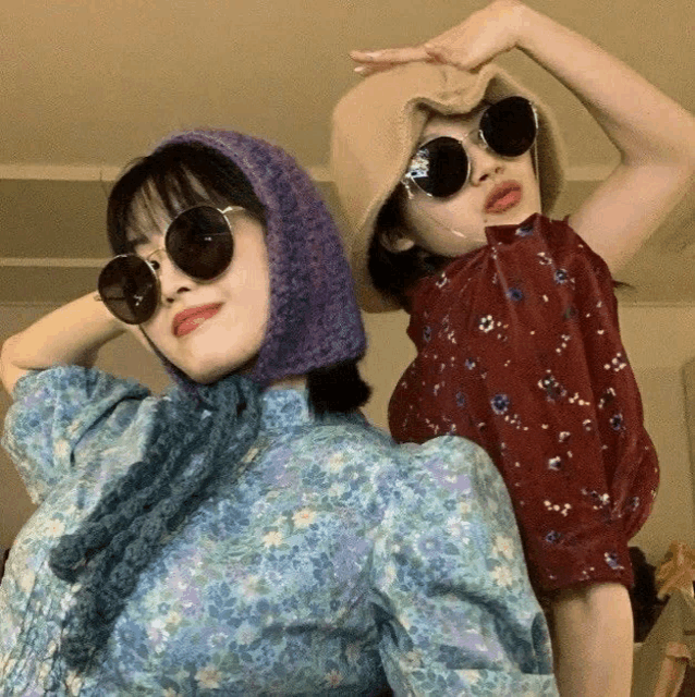 two girls wearing sunglasses and hats pose for a picture