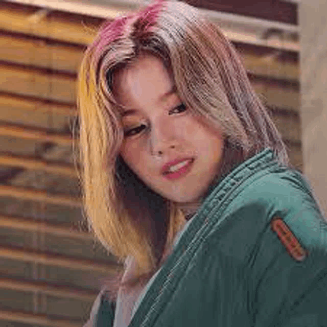 a close up of a woman wearing a green jacket and a white shirt .