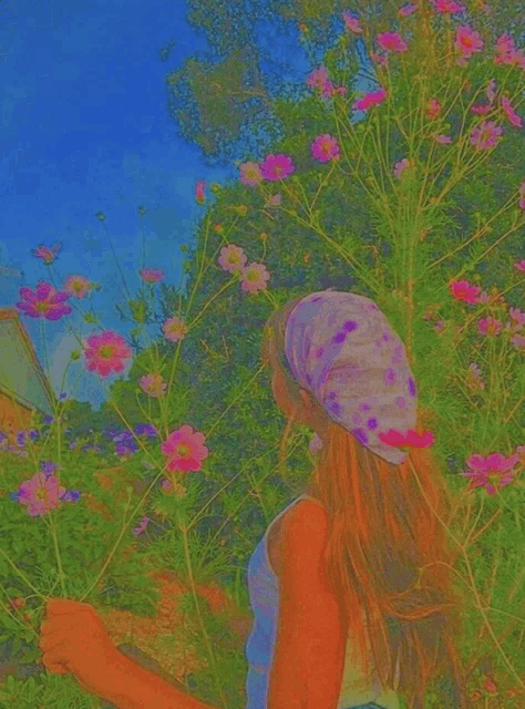 a girl with a bandana on her head is standing in a field of pink flowers