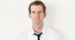 a man in a white shirt and tie is standing against a white wall .