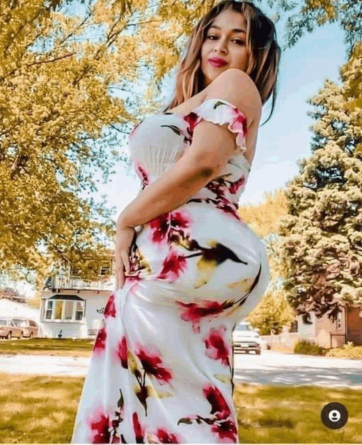 a woman in a floral dress is standing in front of a house .