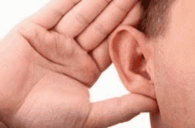 a man is putting his hand to his ear to hear something .