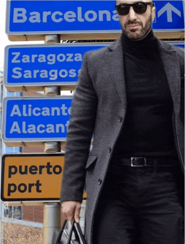 a man wearing sunglasses stands in front of a sign that says puerto port