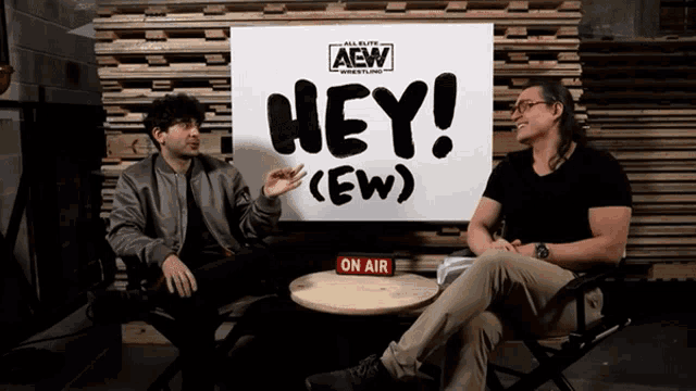 two men sitting in front of a sign that says hey ( ew )