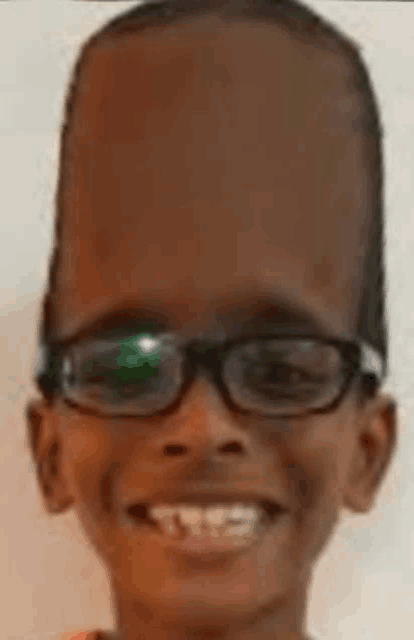 a young boy wearing glasses and a very large head is smiling .