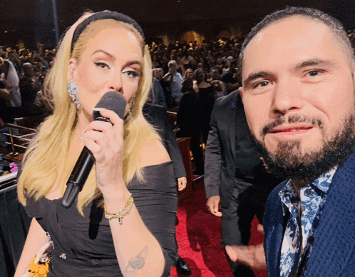 a woman with blonde hair is holding a microphone next to a man with a beard