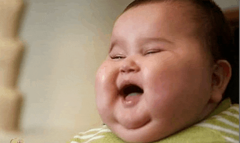 a very fat baby is laughing with his mouth open and his eyes closed .