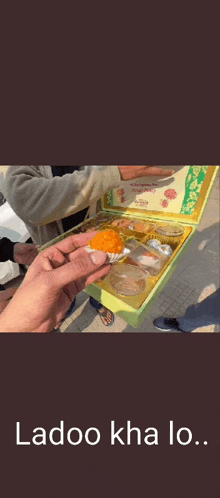 a man with a beard is eating a piece of food with the words ladoo kha lo on the bottom .