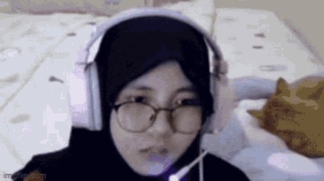 a woman wearing a hijab and headphones looks at the camera .