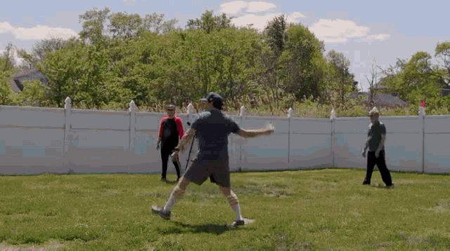 a man is swinging a bat in a backyard while wearing a shirt that says ' ufc ' on the back