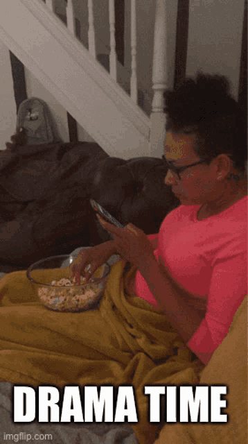 a woman is sitting on a couch eating popcorn and looking at her phone with the caption " drama time " below her