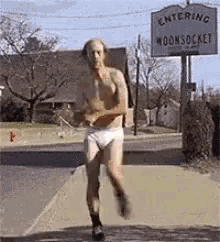 a shirtless man in underwear is running down a sidewalk .