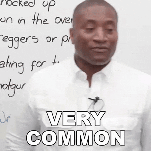 a man in a white shirt is standing in front of a white board and says very common