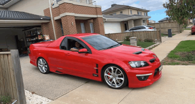 a red car is parked in a driveway in front of a house