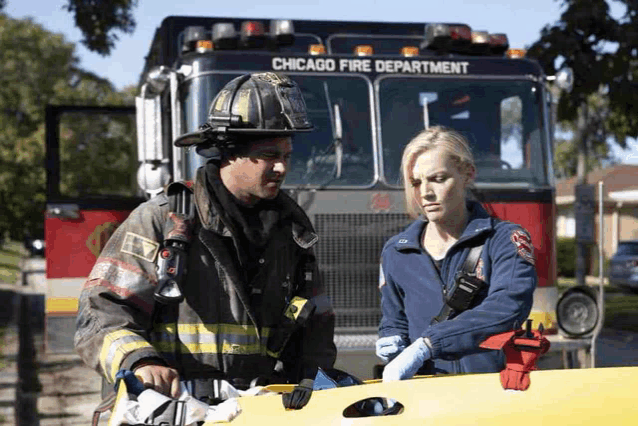 a fireman and a paramedic stand in front of a chicago fire department fire truck