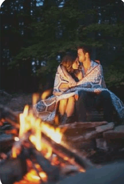 a man and a woman are sitting next to a fire .