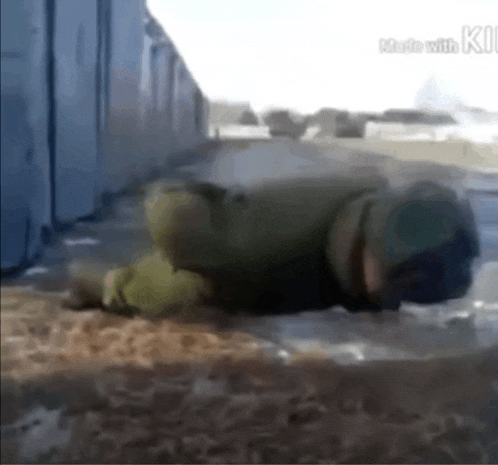 a soldier is laying on the ground in front of a blue container .