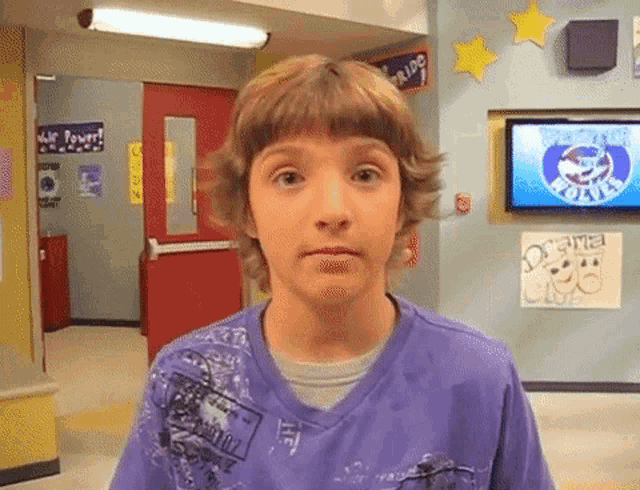 a young boy wearing a purple shirt is standing in front of a tv screen that says ' florida '