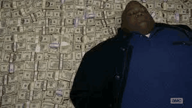 a man is laying on a bed covered in money .