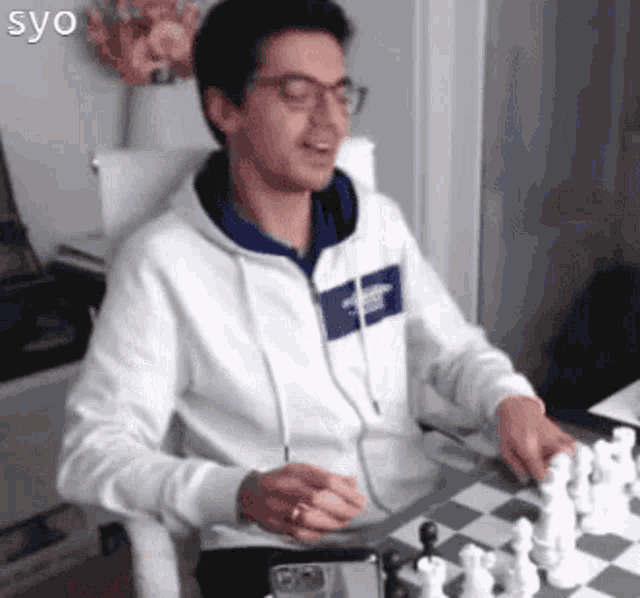 a man is playing a game of chess while wearing glasses .