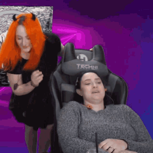 a woman with red hair is standing next to a woman in a techni chair