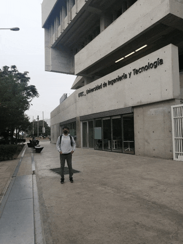 a man wearing a mask is standing in front of a building that says universidad de ingenieria y tecnologia