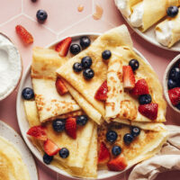 Plate of folded gluten-free crepes topped with fresh berries