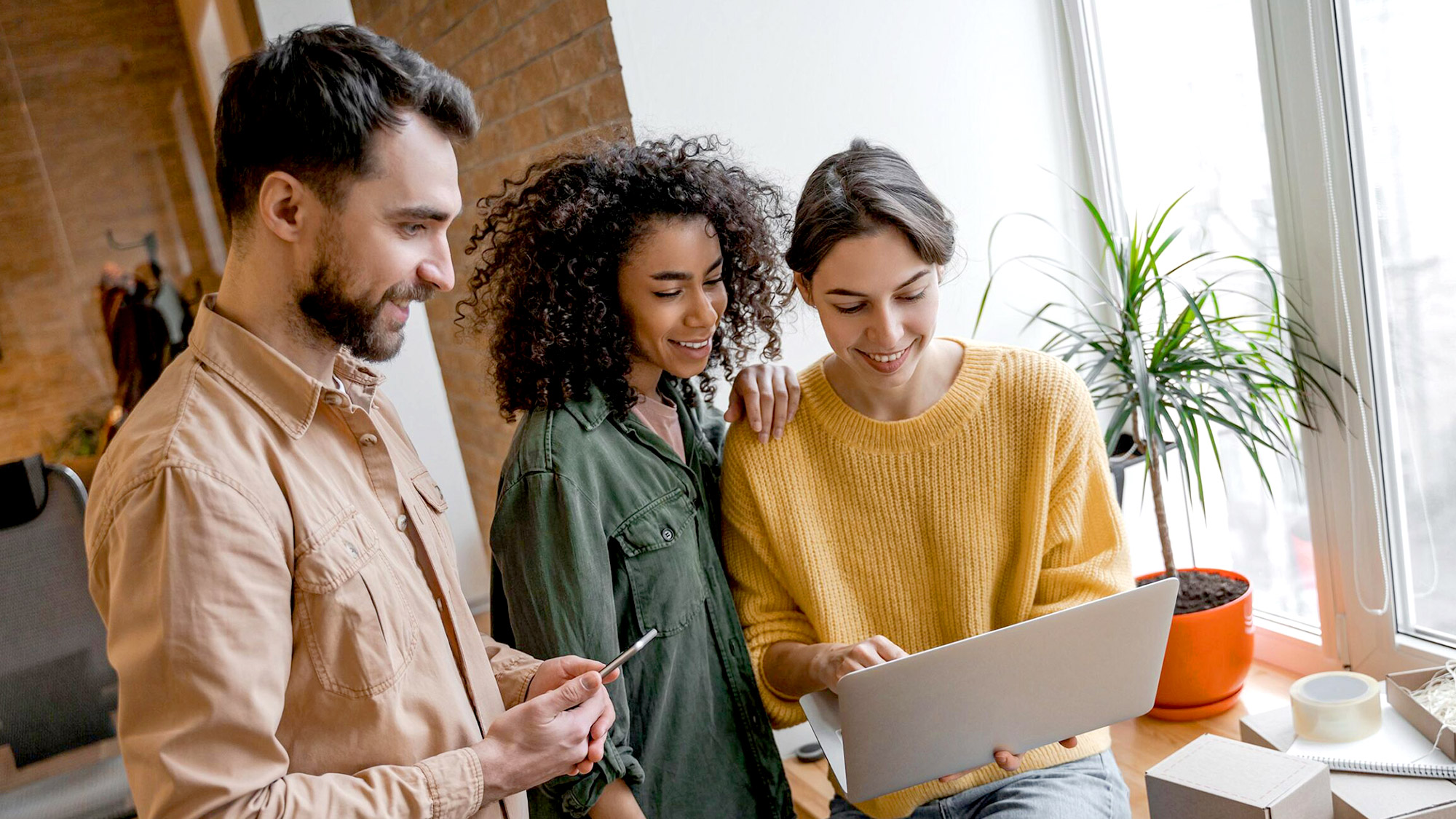 Three professionals gathered around laptop in bright space