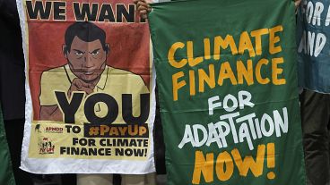 Demonstranten halten Plakate mit der Forderung nach Klimafinanzierung auf der COP29, 23. November 2024