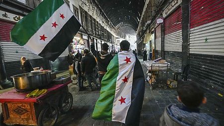 Anhänger der Opposition tragen Oppositionsfahnen auf dem Al-Hamidiyeh-Markt in der alten Stadtmauer von Damaskus, Syrien, Dienstag, 10. Dezember 2024