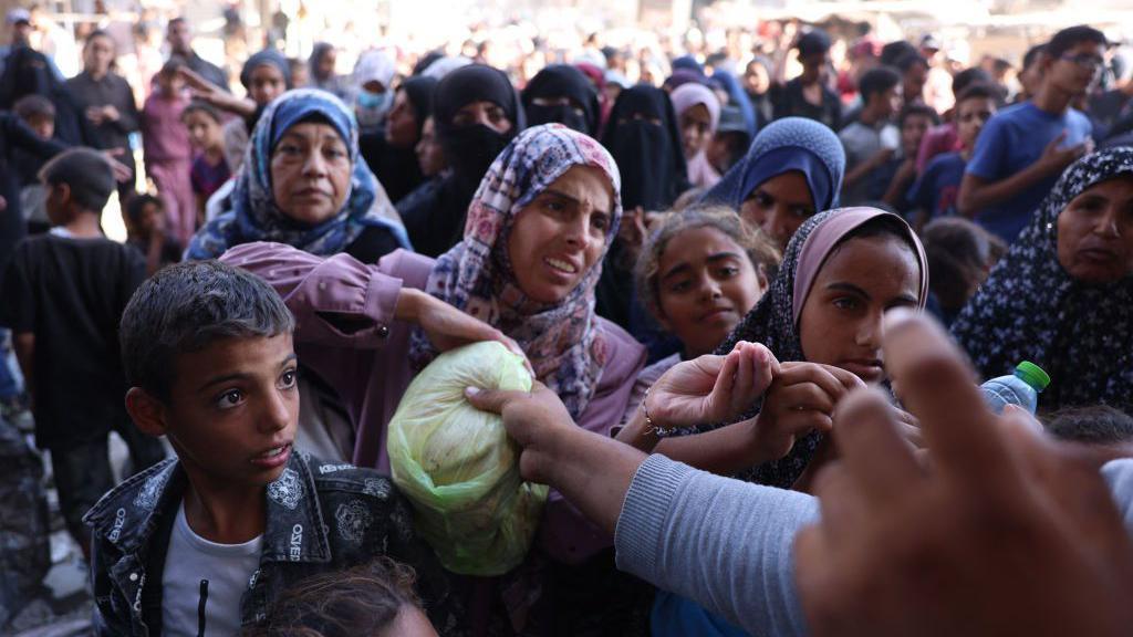 Palestinians wait in a queue to receive bread outside a bakery in Khan Younis, in the southern Gaza Strip (29 October 2024)