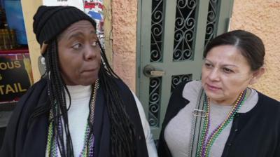 Two women stood on a street in New Orleans, they are both looking in different directions