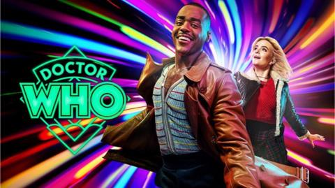 Doctor Who, The Doctor is a young black man wearing a long brown coat, he is running and smiling, his friend Ruby follows behind, she is a younger white woman with shoulder length blonde hair and a blue jacket, they are running through a colourful vortex.