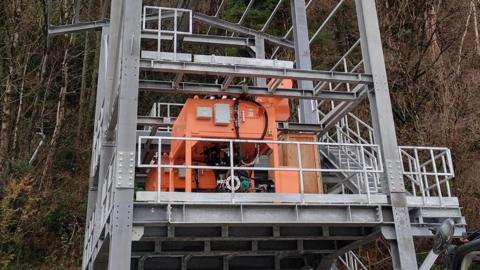 A steel frame surrounds an orange piece of equipment at Lochaline sand mine.